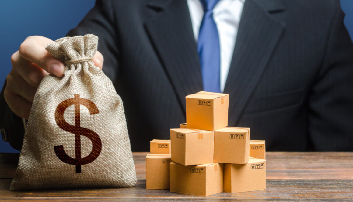 Businessman holds dollar money bag and boxes with goods. Purchase and sale of goods, trade and commerce. Import and export. Business income. Payment of taxes and fees. Advertising budget