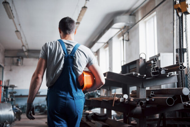 Portrait of a young worker in a hard hat at a large waste recycling factory. The engineer monitors the work of machines and other equipment